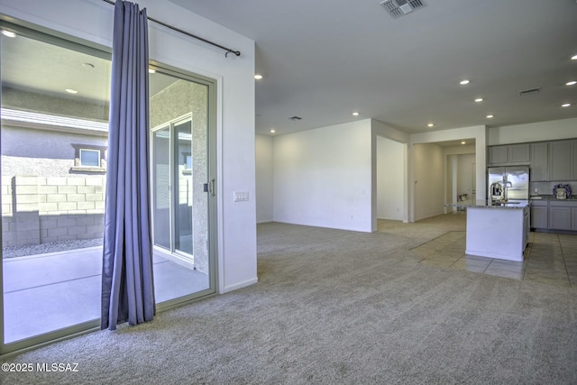 unfurnished living room featuring light carpet, visible vents, recessed lighting, and a sink