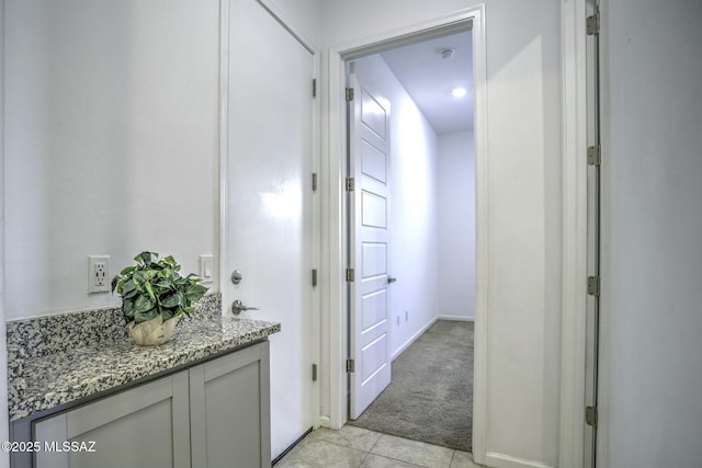 hallway with light tile patterned flooring and light carpet