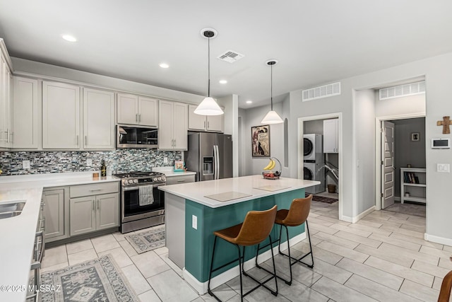 8707 N Ash Grove Ct, Tucson, AZ 85742 - kitchen featuring appliances with stainless steel finishes, estacked washer and dryer, tasteful backsplash, a kitchen island, and light countertops