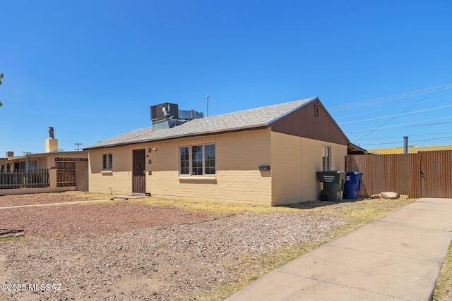 ranch-style house featuring brick siding, central AC, and fence