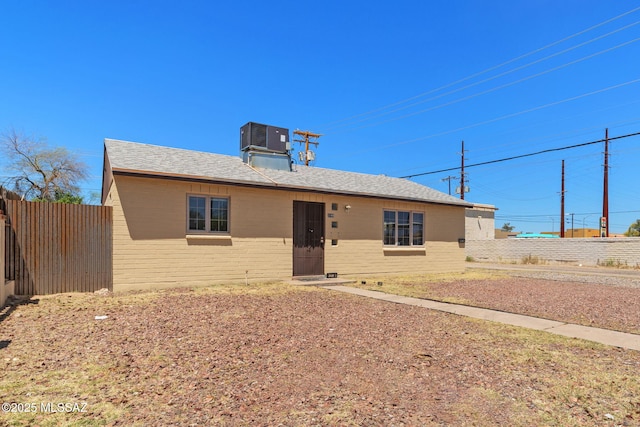 ranch-style house with fence, brick siding, central AC, and a shingled roof