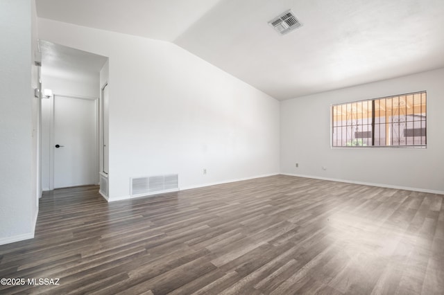 empty room with visible vents, lofted ceiling, baseboards, and dark wood-style flooring