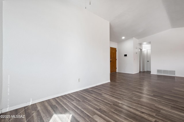 spare room with dark wood-style floors, visible vents, baseboards, and vaulted ceiling