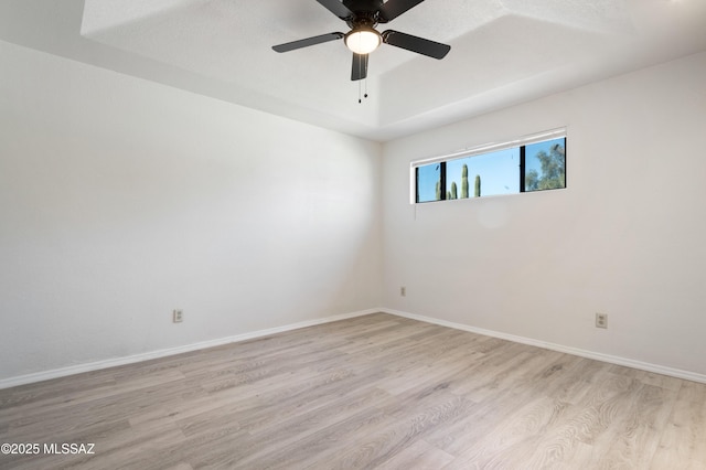 empty room with a ceiling fan, light wood-style floors, and baseboards