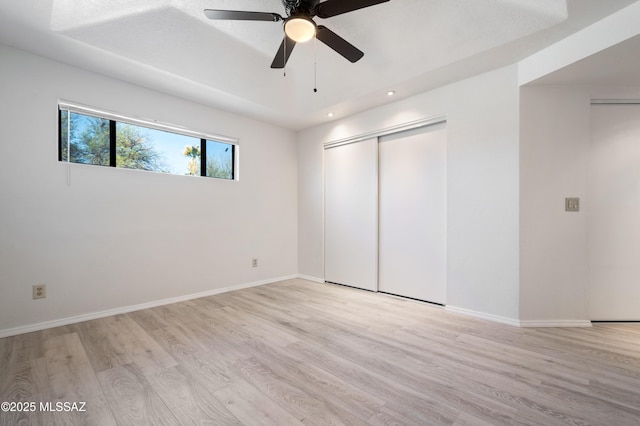 unfurnished bedroom featuring a closet, ceiling fan, baseboards, and light wood-style floors