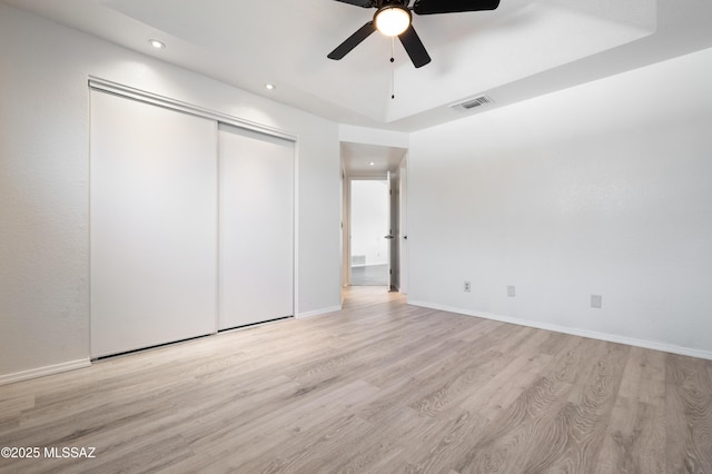 unfurnished bedroom featuring a ceiling fan, wood finished floors, visible vents, baseboards, and a closet