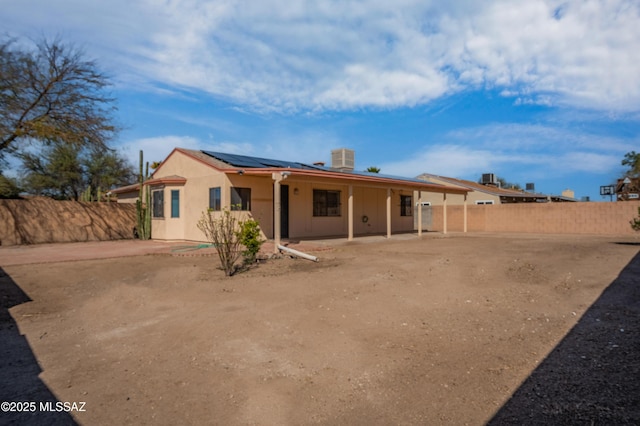 back of house with central AC unit, a fenced backyard, stucco siding, a patio area, and roof mounted solar panels