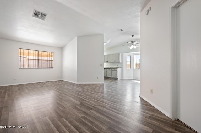 unfurnished living room featuring visible vents, ceiling fan, baseboards, vaulted ceiling, and dark wood-style floors