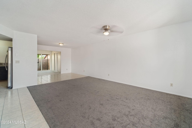 unfurnished room featuring light tile patterned floors, light carpet, a textured ceiling, and a ceiling fan