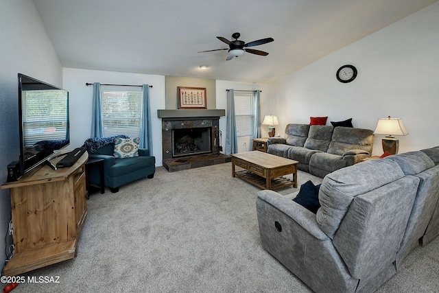 carpeted living room with a tiled fireplace, vaulted ceiling, and a ceiling fan