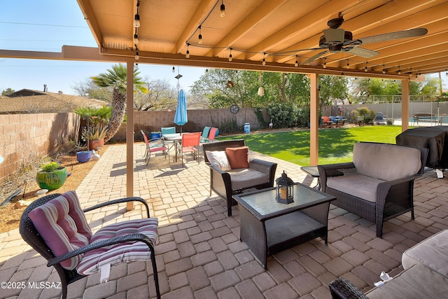 view of patio with grilling area, an outdoor living space, a fenced backyard, outdoor dining space, and a ceiling fan