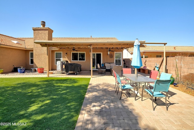 rear view of property featuring stucco siding, a lawn, a patio area, and fence