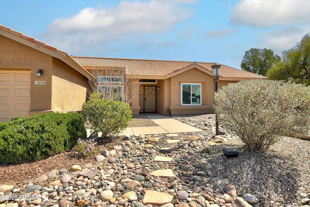 view of front of home with a tile roof, an attached garage, and stucco siding