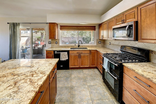 kitchen featuring light stone countertops, brown cabinets, a sink, black appliances, and tasteful backsplash