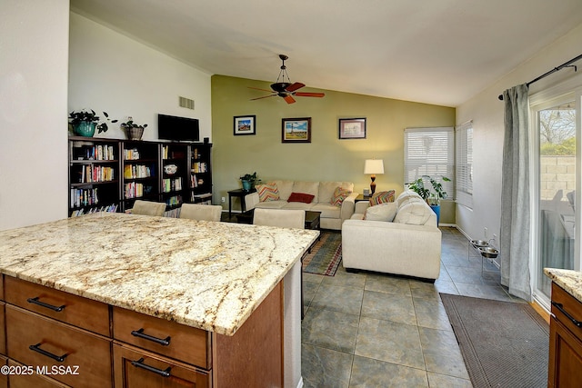 kitchen with vaulted ceiling, light stone countertops, and open floor plan