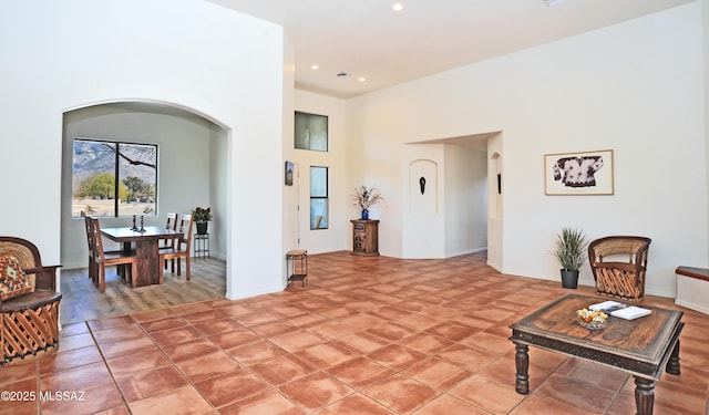 living area featuring recessed lighting, arched walkways, and a towering ceiling