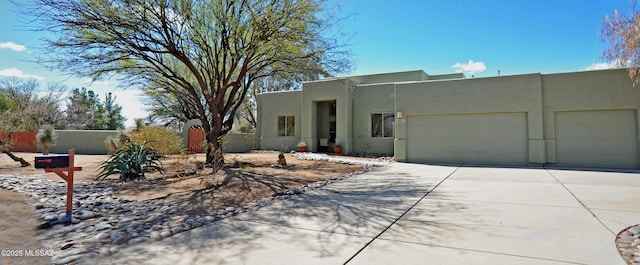 adobe home with concrete driveway, fence, a garage, and stucco siding