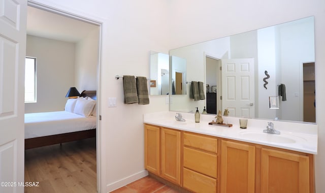 ensuite bathroom featuring double vanity, ensuite bathroom, baseboards, and a sink