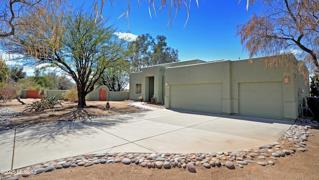 view of front of property featuring an attached garage, fence, and stucco siding