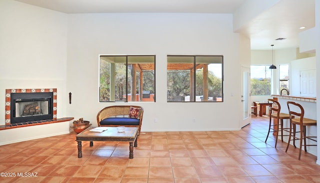 sitting room with light tile patterned floors, visible vents, a tile fireplace, and baseboards