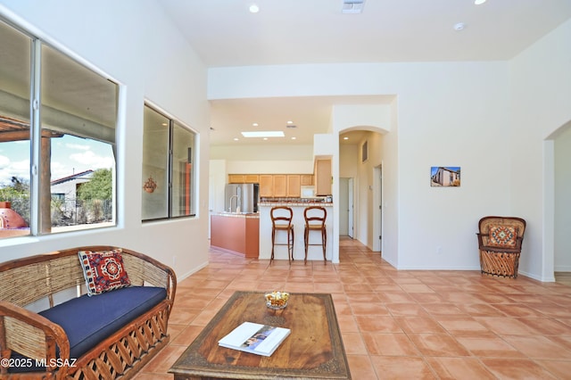 living room with light tile patterned flooring, recessed lighting, arched walkways, and baseboards