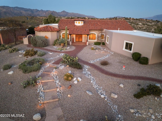 view of front of house featuring a patio, driveway, stucco siding, a tile roof, and a mountain view