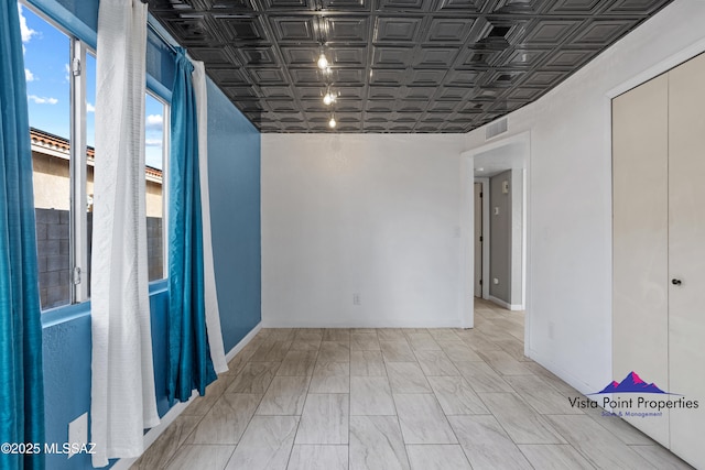 unfurnished room featuring visible vents, an ornate ceiling, and baseboards