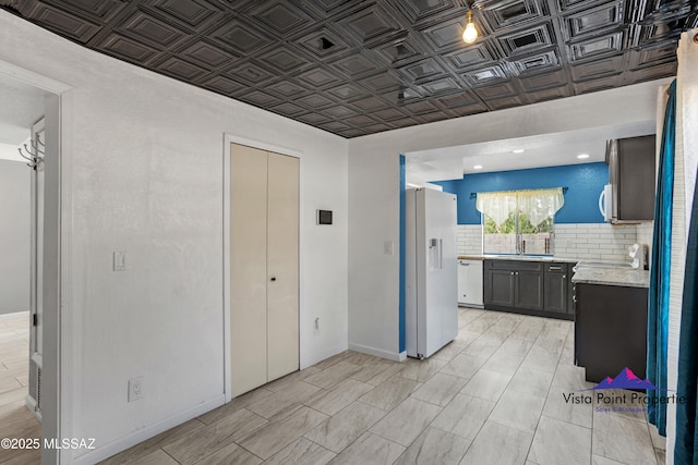 kitchen with white appliances, baseboards, an ornate ceiling, a sink, and tasteful backsplash