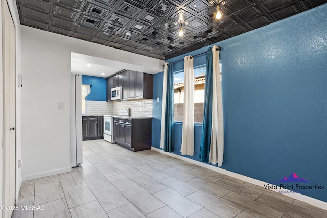 kitchen featuring backsplash, an ornate ceiling, baseboards, light countertops, and white appliances