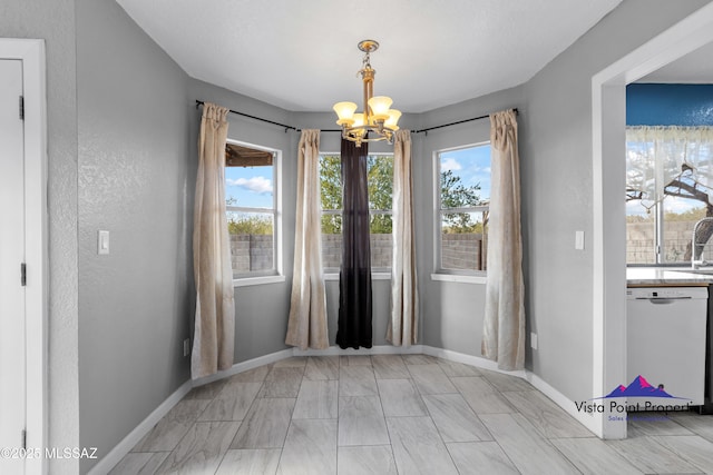 unfurnished dining area featuring a sink, baseboards, and an inviting chandelier