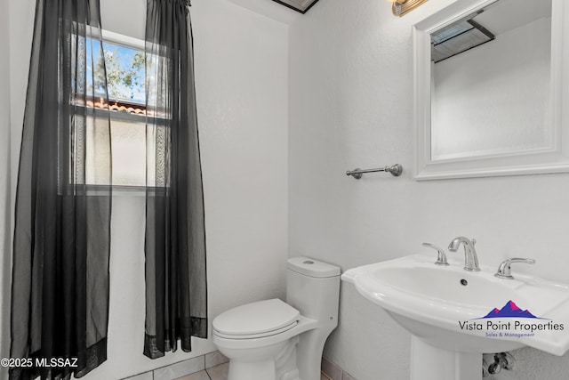 bathroom with a sink, toilet, and tile patterned floors