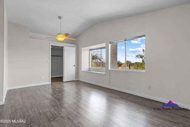 unfurnished bedroom featuring a closet, baseboards, dark wood-style flooring, and vaulted ceiling