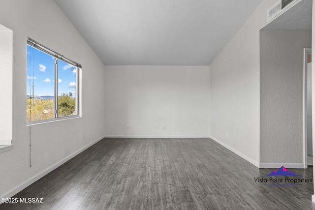 spare room featuring visible vents, baseboards, lofted ceiling, and wood finished floors