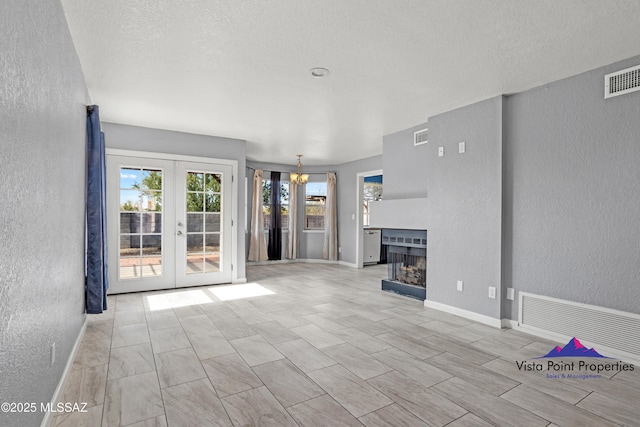 unfurnished living room with visible vents and a textured wall