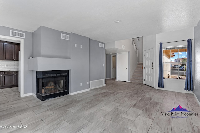 unfurnished living room with visible vents, a fireplace, and stairway