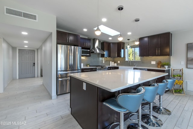 5391 W El Camino Del Cerro, Tucson, AZ 85745 - kitchen featuring stainless steel appliances, wall chimney exhaust hood, dark brown cabinets, a sink, and a kitchen island