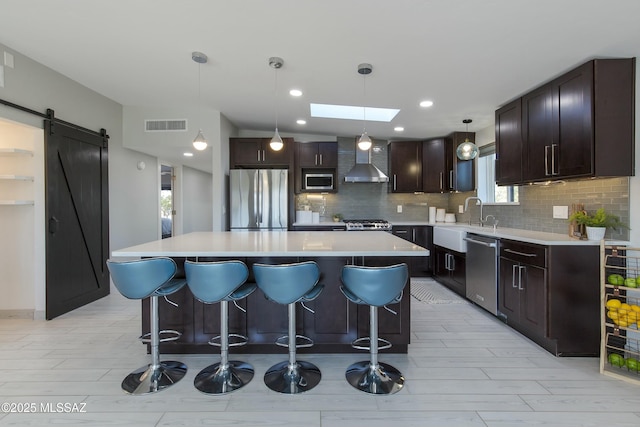5391 W El Camino Del Cerro, Tucson, AZ 85745 - kitchen featuring stainless steel appliances, wall chimney range hood, a sink, a barn door, and decorative backsplash