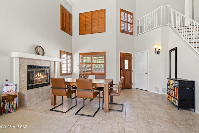715 W Annandale Way, Tucson, AZ 85737 - dining area featuring a towering ceiling, a tile fireplace, stairway, baseboards, and tile patterned floors