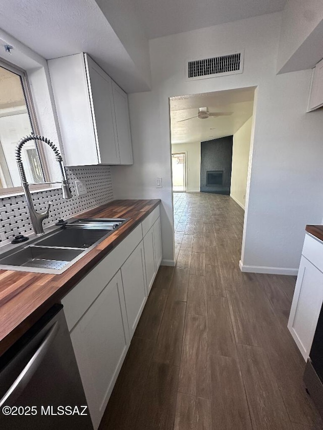 kitchen featuring visible vents, a sink, decorative backsplash, wood counters, and stainless steel dishwasher