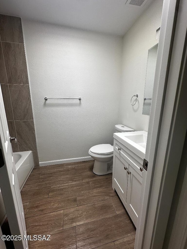 bathroom with vanity, toilet, wood finished floors, and baseboards