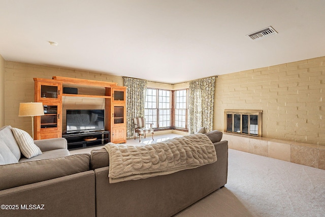 carpeted living room with visible vents, a brick fireplace, and brick wall