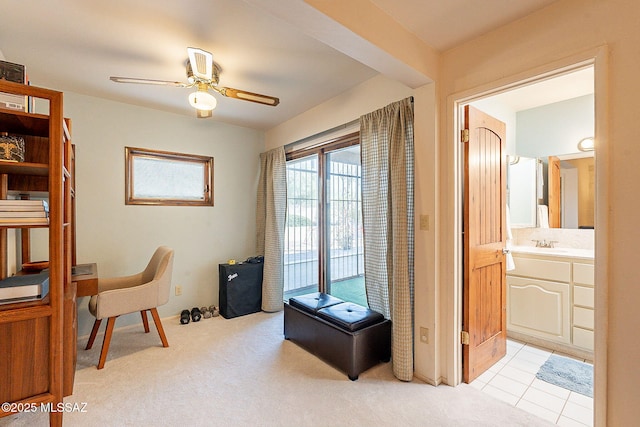 office featuring a sink, light colored carpet, ceiling fan, and light tile patterned flooring