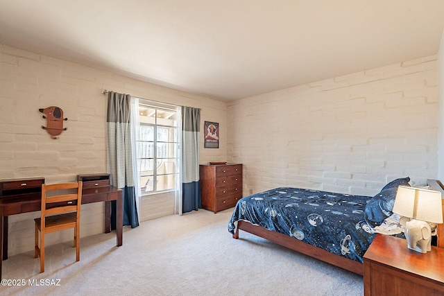 bedroom featuring brick wall and light carpet