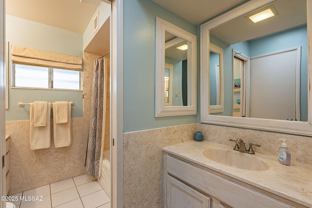 full bath with a wainscoted wall, shower / tub combo with curtain, vanity, and tile patterned flooring