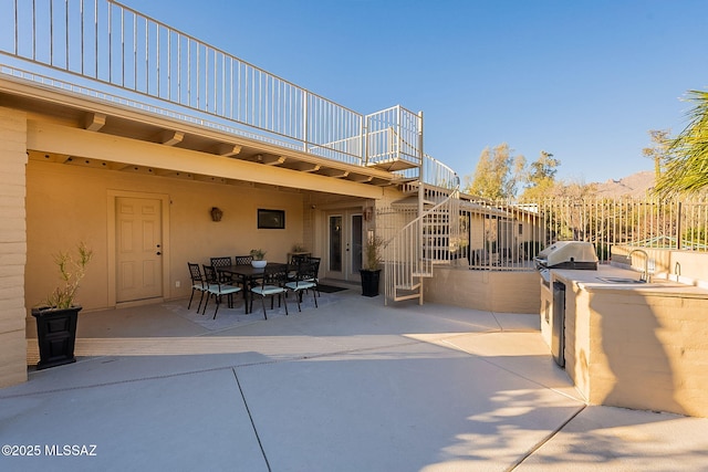 view of patio / terrace with stairs, outdoor dining space, area for grilling, a grill, and a sink