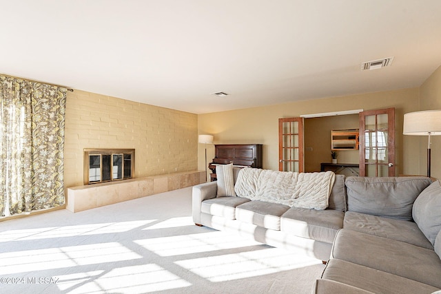 living area with visible vents, carpet floors, and a large fireplace