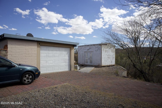 detached garage with a shed and decorative driveway