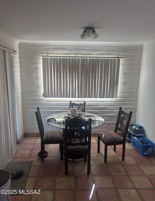 dining space featuring tile patterned floors and brick wall