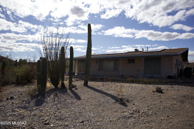 rear view of property featuring roof mounted solar panels