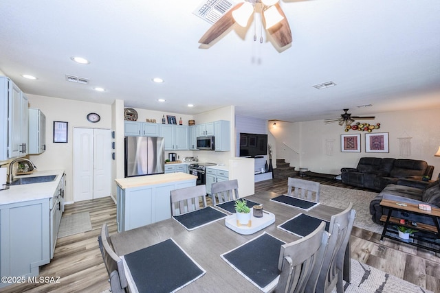 dining space with visible vents, light wood-style floors, ceiling fan, and stairway